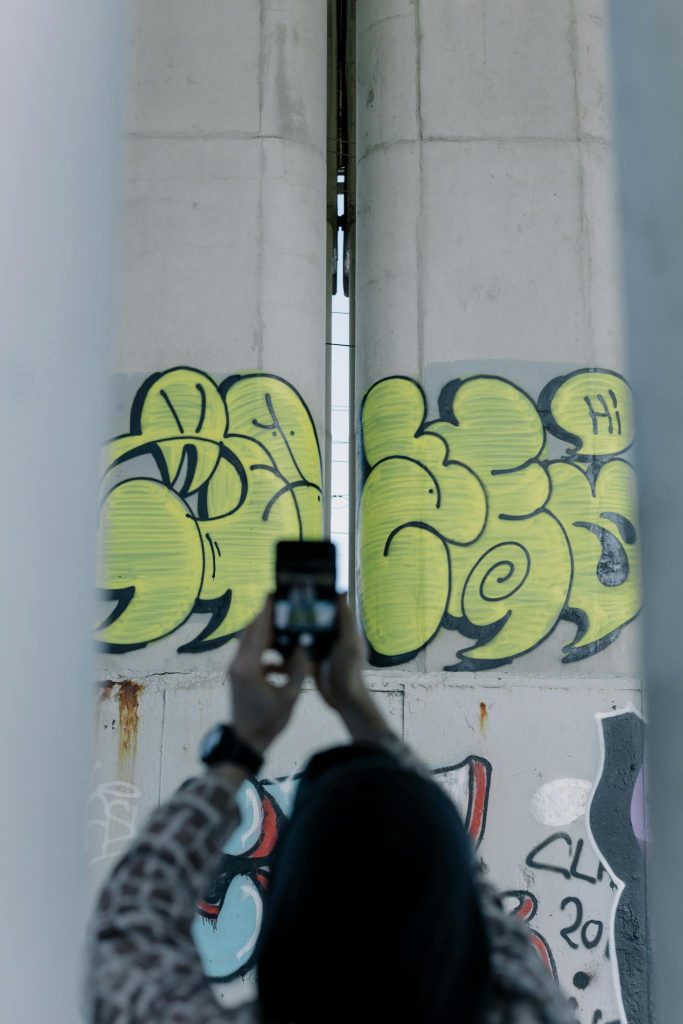 Anonymous blogger taking photo of graffiti wall on smartphone