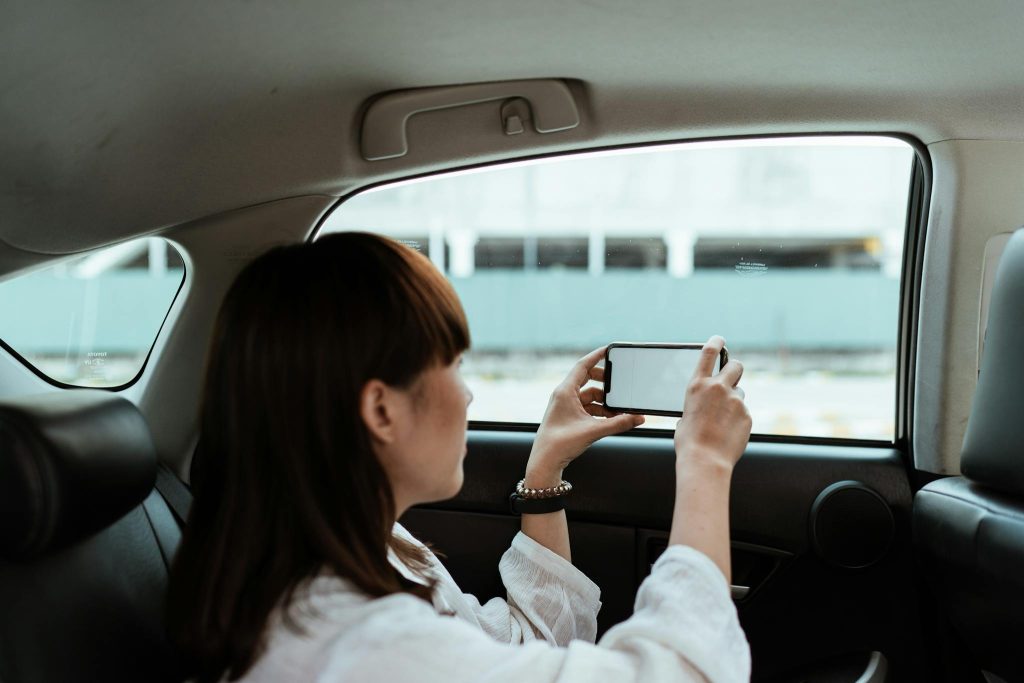 Anonymous female tourist taking photo on smartphone sitting in car